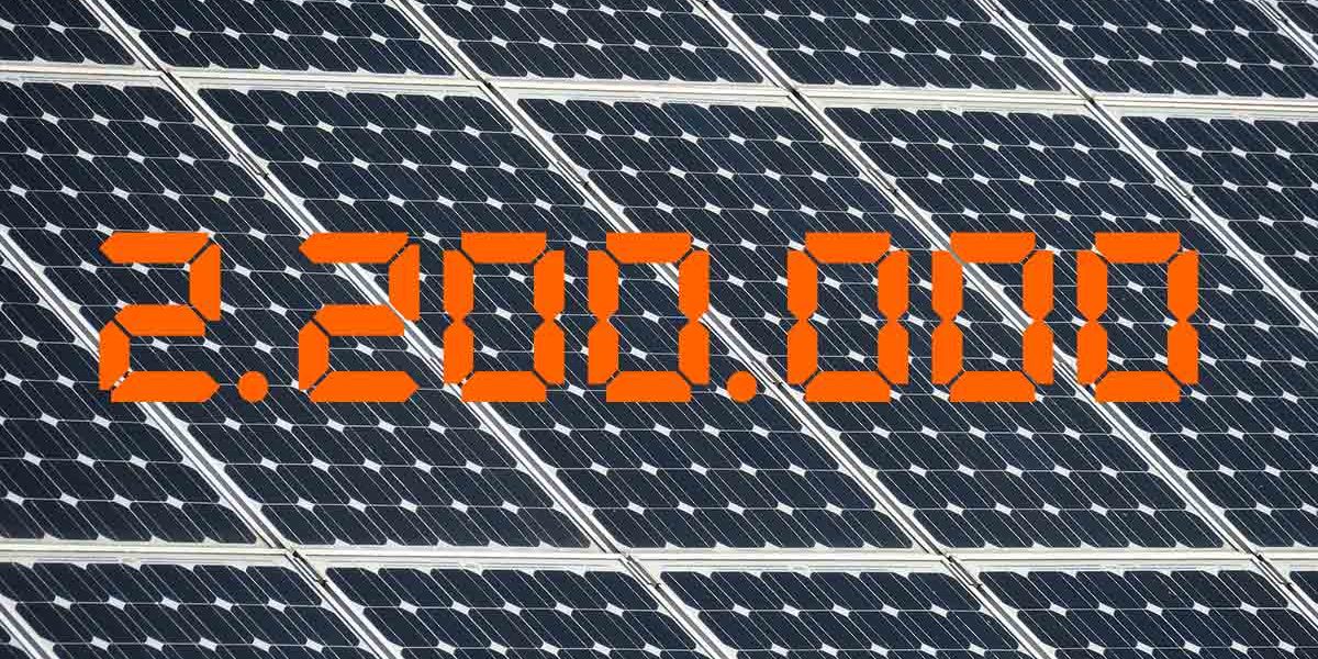 Die Zahl 2,2 Millionen in Orange vor einem Hintergrund aus Solarpaneelen - Photovoltaik