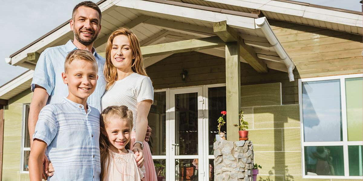 Glückliche Familie vor Effizienzhaus 40, das vom Staat gefördert wurde.