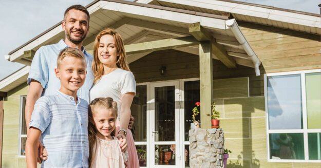 Glückliche Familie vor Effizienzhaus 40, das vom Staat gefördert wurde.