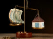 Scale with money and model of house on dark background; Wertermittlung