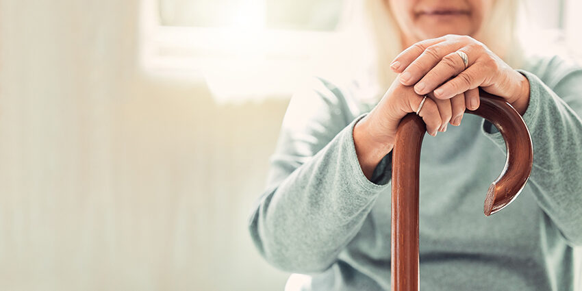 Growing old is inevitable, but growing up is optional. elderly woman resting her hands on her walking stick while relaxing at home; Wohnen im Alter