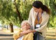 Eine Seniorin in ihrem Rollstuhl und ihre Pflegerin