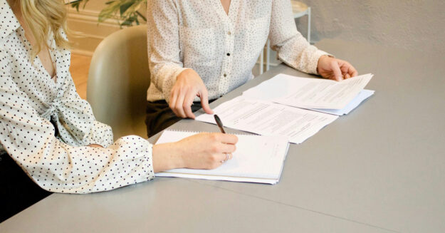 Eine Immobilienkäuferin unterzeichnet den Kaufvertrag bei einer Notarin | Immobilienverkauf