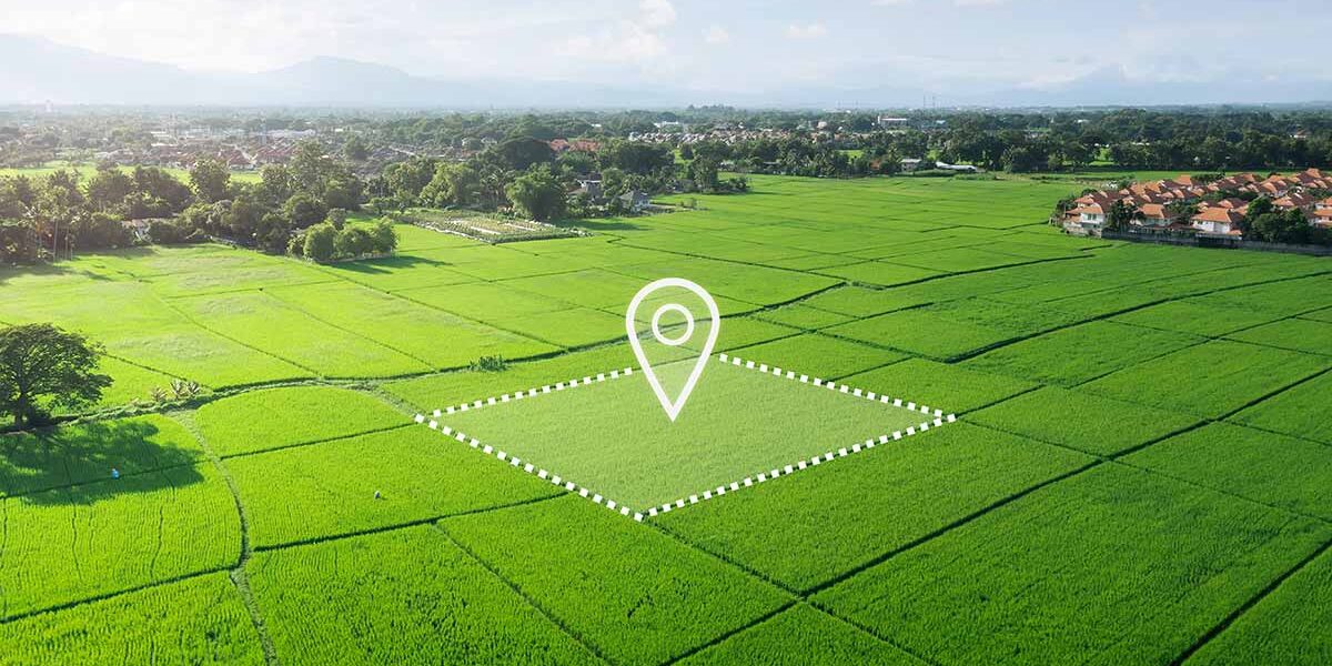 Luftaufnahme eines unbebauten, grünen Grundstücks mit markierter Fläche und Standort-Symbol, das die Entwicklungsmöglichkeiten und den gezielten Verkauf von Bauland veranschaulicht. | Grundstücksverkauf